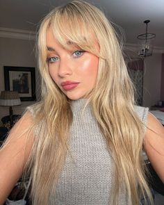 a woman with blonde hair and blue eyes posing for a photo in her living room