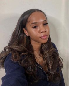 a woman with long brown hair is looking at the camera while wearing a blue jacket