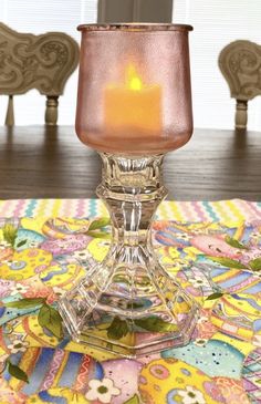 a glass candle holder sitting on top of a table