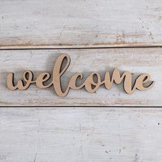 a wooden sign that says welcome on the side of a white painted wood planked wall