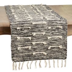 the black and white table runner is on top of a wooden table with a wood bench