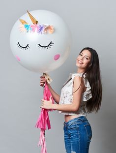 a woman holding a balloon with a unicorn face on it