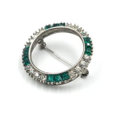 "Stunning vintage sterling rhinestone circle brooch. These rhinestones have a beautiful sparkle when they hit the light. It is unsigned but is very well made. The green rhinestones are open backed. All of the rhinestones are in good condition.  Marked \"Sterling\" and tested to guarantee purity.  In good vintage condition.  Measures: 1.17\" Diameter Weighs: 7.12 grams Please feel free to contact me with questions and/or for additional photos. More classic rhinestone pieces in the shop: Austrian rhinestone bow brooch - https://etsy.me/3QRsSYY Victorian sterling paste rhinestone clover brooch - https://etsy.me/3wimBxQ *Free Domestic Shipping on Orders Over $35* All orders ship USPS First Class. If you would like to add insurance please reach out before purchase. All of our items are in good, Formal Green Rhinestone Brooches, Luxury Green Diamond Brooches, Silver Rhinestone Round Brooches, Clover Brooch, Vintage Green Diamond Brooches, Vintage Green Rhinestone Brooch, Rhinestone Bow, Brooch Pin, Brooches