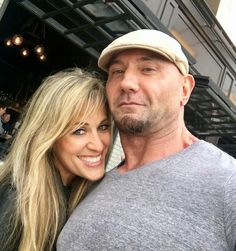 a man and woman taking a selfie in front of a restaurant with their arms around each other