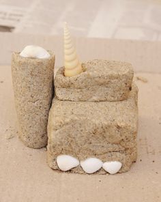 two toothbrush holders made out of sand on top of a piece of brown paper