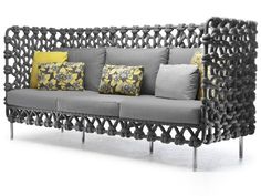 a gray couch with yellow and grey pillows on it's armrests, sitting in front of a white background