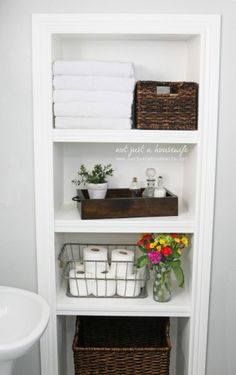 a white shelf filled with lots of towels and flowers