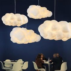 two people sitting at a table under clouds hanging from the ceiling