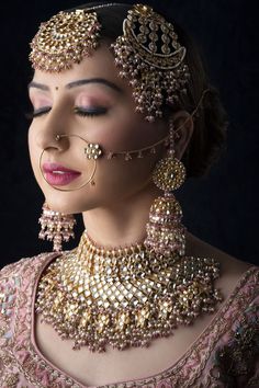 a woman wearing an elaborate necklace and earring with jewelry on her face, in front of a black background