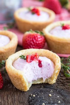 small desserts with strawberries and cream in them on top of a wooden table