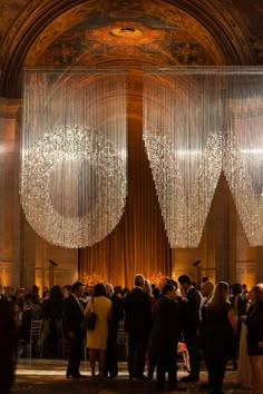 a group of people standing in front of a large chandelier hanging from the ceiling