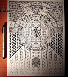 an intricate drawing on paper with a pen next to it