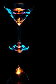 two martini glasses sitting side by side on a black background, one is blue and the other is yellow