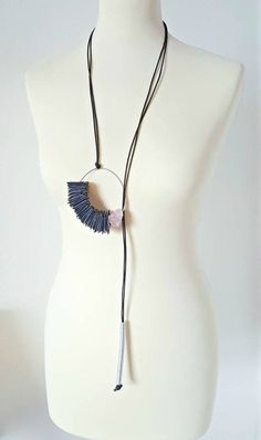 a white mannequin with a necklace on it's neck and a black tassel