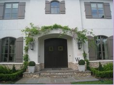 the front entrance to a large white house with ivy growing on it's walls