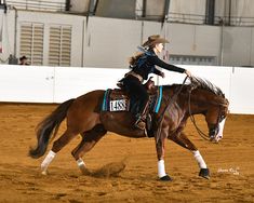 a woman riding on the back of a brown horse in an arena at a rodeo