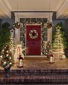 christmas decorations on the front steps of a house with wreaths and lights around them