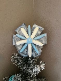 a blue and white flower decoration on top of a christmas tree in a corner room