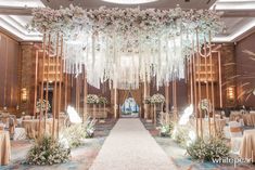 an elegant wedding setup with white flowers and greenery on the ceiling, along with chandeliers