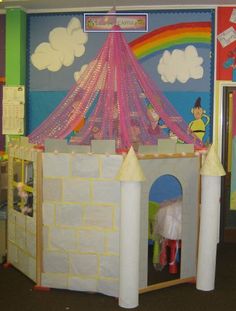 there is a castle made out of cardboard and paper machs on the wall, with a rainbow in the background