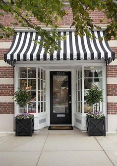 a black and white striped awning on the front of a building with potted plants