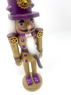 a nutcracker figurine wearing a purple hat and gold trimmings