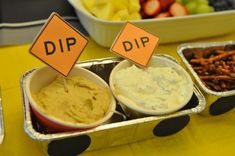 dips and other foods are sitting in small trays on a yellow tablecloth