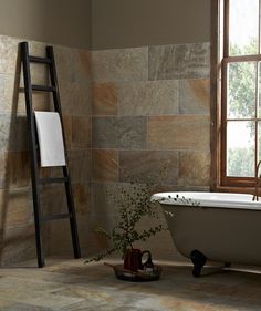 a bath tub sitting next to a window with a ladder on it's side