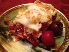 a piece of pie on a plate with cherries and whipped cream drizzled over it