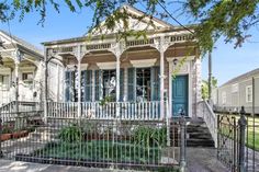 a white house with blue shutters on the front porch and stairs leading up to it