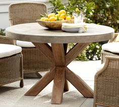 an outdoor table with two chairs and a bowl of fruit on it's top