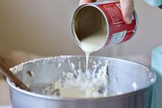 a person pouring batter into a metal bowl