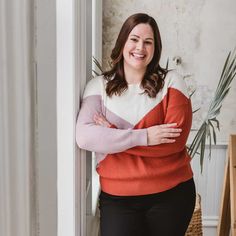 a woman standing in front of a door with her arms crossed and smiling at the camera