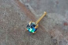 a close up view of a blue and green jeweled earring on a rock