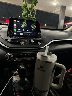 a car dashboard with a cup and cell phone on it, next to a coffee mug