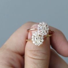 a woman's hand holding an engagement ring with three diamonds on top of it