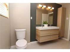 a white toilet sitting next to a sink in a bathroom under two lights and a mirror