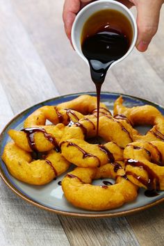 someone pouring sauce on some doughnuts on a plate