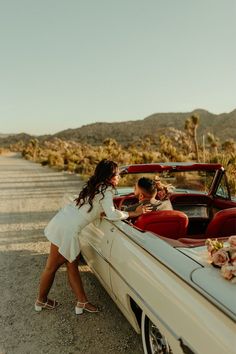 a woman leaning on the back of a white car