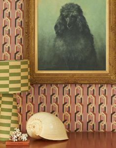 a large black dog sitting in front of a painting on the wall next to a sea shell