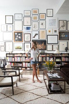 a woman standing in front of a living room filled with furniture and bookshelves