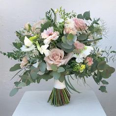 a bouquet of flowers sitting on top of a white table next to a gray wall