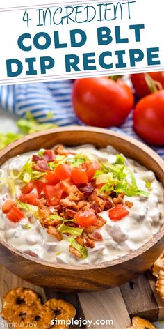 a wooden bowl filled with dip next to crackers and tomatoes