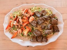 a white plate topped with meat and veggies on top of a wooden table