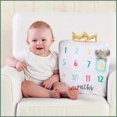 a baby sitting on a chair next to a calendar