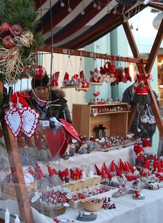 a table topped with lots of red and white christmas decorations next to a man in a black jacket