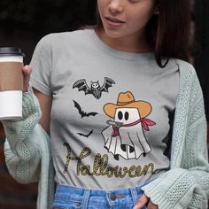 Yee-haw! Get ready to ride into the spooky season with our Cowboy Ghost tee. This ghost may be from the afterlife, but he's still got his cowboy hat, bandana, and trusty pistol to keep things wild. With bats flying and a skeleton bat watching his back, this ghost is ready for a hauntingly good time. Perfect for lovers of the Wild West and all things spooky, this shirt is your go-to for Halloween fun! Crafted from soft, breathable fabric, this unisex jersey short sleeve tee offers long-lasting comfort and style. The lightweight material (4.2 oz/yd²) makes it ideal for layering or wearing solo, while the ribbed knit collar and tapered shoulders ensure a great fit that holds its shape. Available in six ghostly colors, this shirt adds a touch of spooky Western flair to your wardrobe. Like all Halloween Cartoon Print T-shirt, Halloween Fan Merchandise Cartoon T-shirt, Halloween Fan Merchandise Cartoon Print T-shirt, Halloween Themed Pre-shrunk T-shirt, Halloween Cartoon Print Fan Merchandise T-shirt, Pre-shrunk Themed T-shirt For Halloween, Spooky Halloween Fan Merchandise T-shirt, Wild West Halloween, Spooky Cowboy