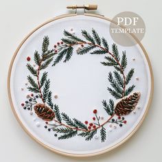 the embroidery pattern has pine cones and berries on it, along with other christmas decorations