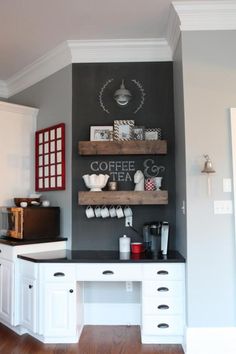 a kitchen with white cabinets and wooden shelves filled with coffee cups on top of them