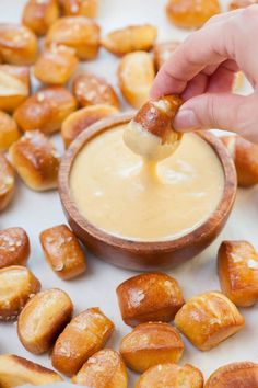 a person dipping something into a small bowl filled with doughnuts and other snacks